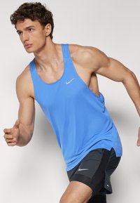 Top atlético sin mangas de color azul, con escote redondo y textura perforada, que presenta un pequeño logo plateado de Nike en el pecho.