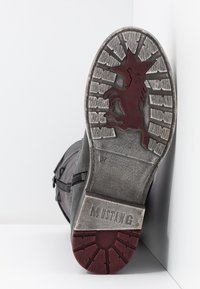 Stivale in pelle nera con suola testurizzata. La suola presenta un logo di stallone rosso e un motivo di battistrada per una migliore aderenza. Dettaglio con zip laterale presente.