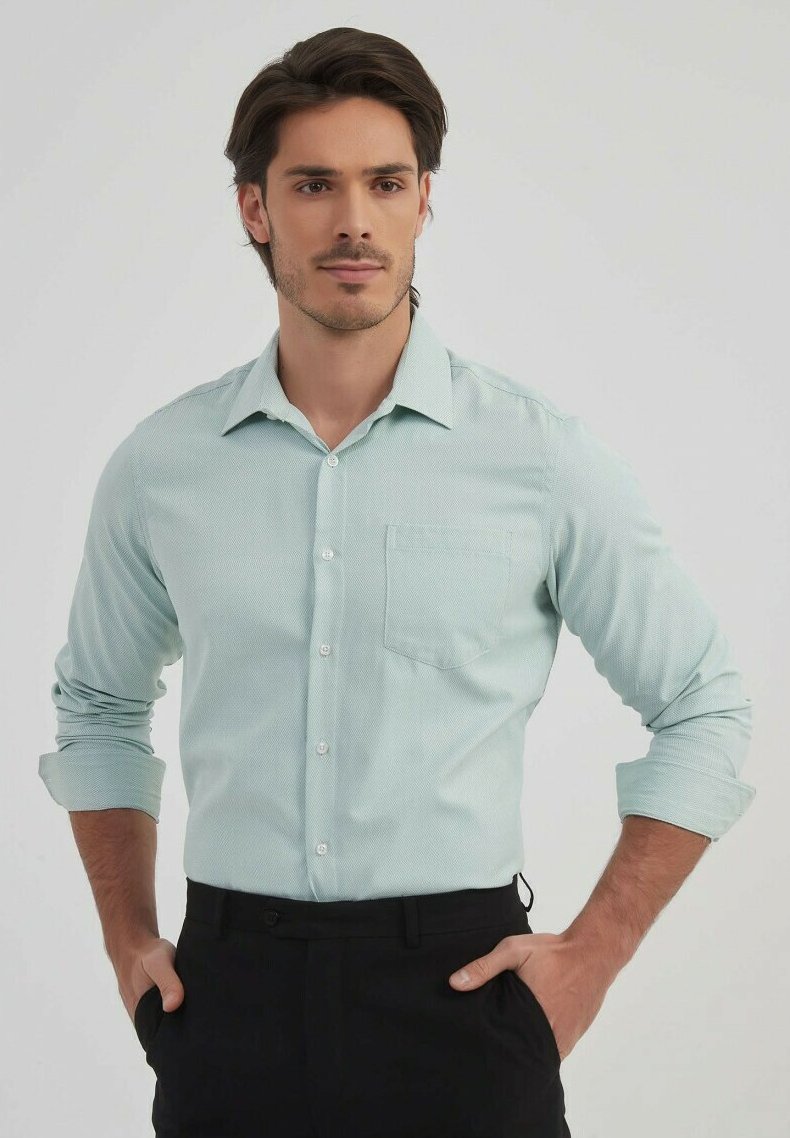 Chemise button-up bleu clair, texturée, à manches longues avec une poche sur la poitrine. Elle présente un col à boutons et des manches retroussées. Portée avec un pantalon sombre.