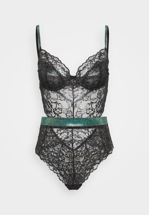 Black lace bodysuit with padded cups, scalloped edges, and a turquoise rhinestone-accented waist detail. Adjustable straps included.