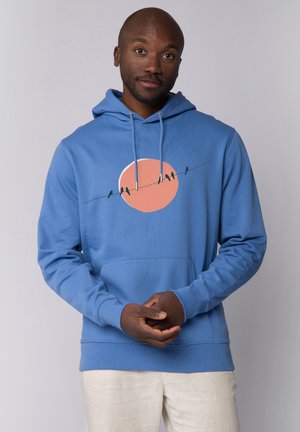 Blauwe hoodie met een kangoeroe zak en een trekkoord. Kenmerkt een afbeelding van vogels op een draad tegen een perziken ronden zon. Zachte textuur.