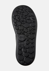 Black rubber shoe sole with circular patterns and textured accents. Features the brand name "Camper" and size markings.