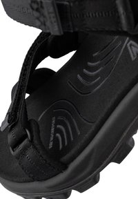 Musta sandaali, jossa on teksturoitu kumipohja, säädettävät nailonhihnat, pehmustettu jalkapohja aaltoilevalla kuviolla ja kestävä muovinen varustus.