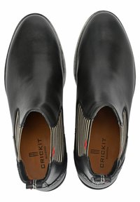 Bottines en cuir noir avec des panneaux latéraux élastiques présentant un motif rayé. L'intérieur est doté d'une doublure marron avec le nom de la marque embossé.