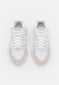 Vita och beige sportskor med ovandel i läder och textil, med tre ränder, runda snören och en vadderad sula.