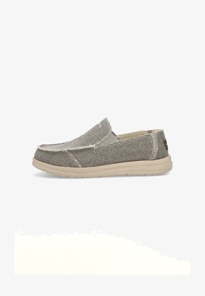 Zapato tipo slip-on en tejido gris texturizado con suela de goma beige, con puntera redondeada y costuras visibles a lo largo de las costuras.