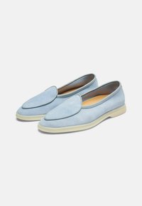 Lichtblauwe suède instap schoenen met een spitse neus, zachte textuur en een contrasterende beige rubberen zool. Elegante stikdetails langs de rand.