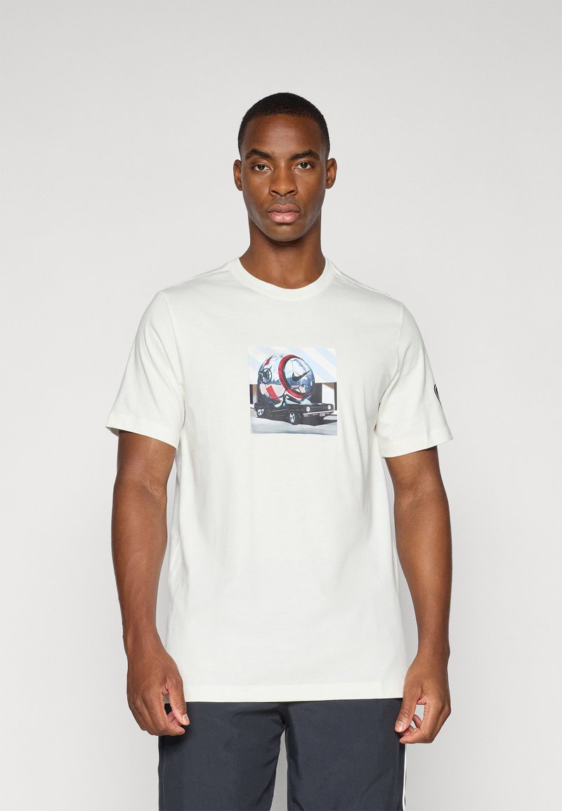 Lys beige t-shirt med rund hals og korte ærmer, der har et grafisk motiv af et køretøj på forsiden, lavet af blødt bomuldsstof.