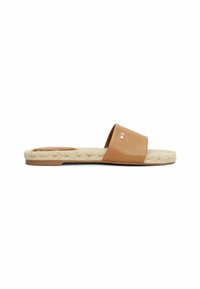 Sandal en tan avec une semelle texturée et une large lanière en cuir avec un petit logo carré métallique sur fond blanc.