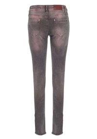 Jean skinny en denim gris avec une finition légèrement délavée, comportant des poches, un détail en cuir brun et des ourlets effilochés.