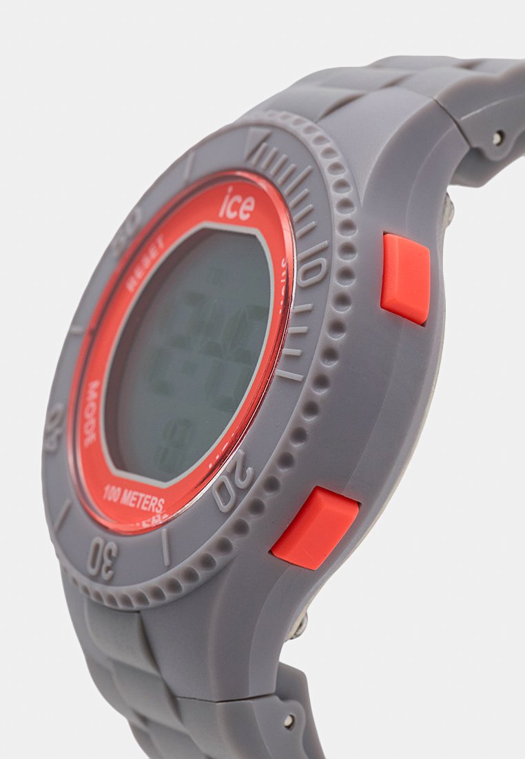 Reloj deportivo digital con correa de silicona gris y bisel redondo rojo. Incluye botones rojos prominentes y resistencia al agua de hasta 100 metros.
