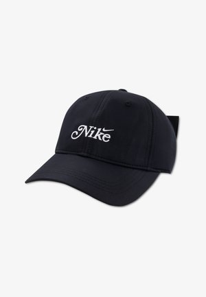 Casquette noire Nike avec une visière courbée, arborant un logo blanc brodé. Fabriquée en tissu texturé avec des œillets pour la ventilation. Sangle ajustable à l'arrière.