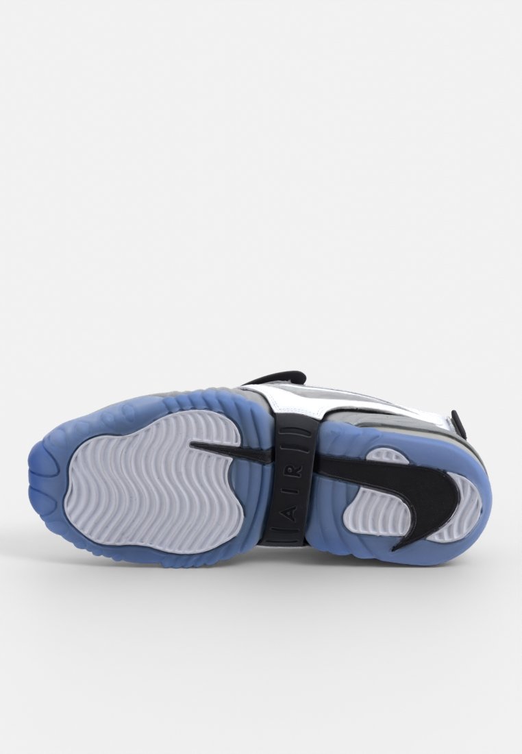 Zapatilla negra y azul con una suela blanca texturizada, que presenta un logo de Nike visible y una correa elegante a lo largo del mediopié.