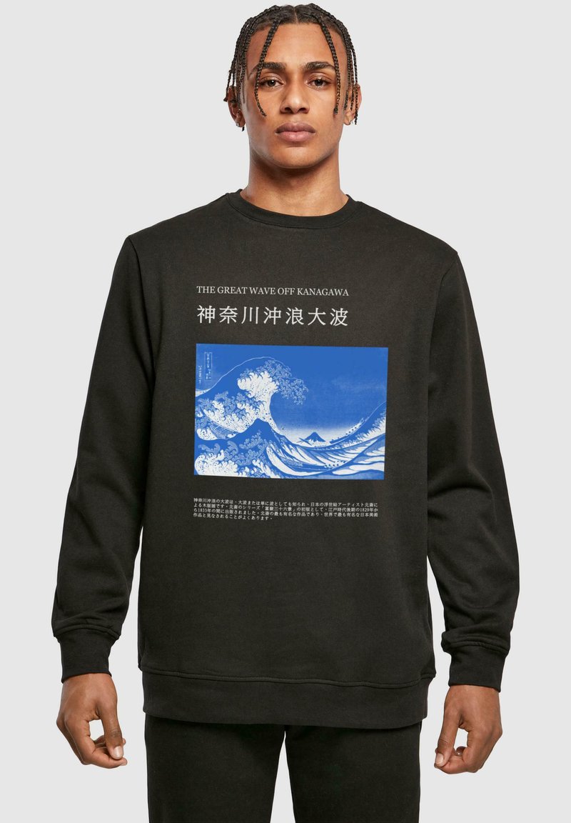Svart hettegenser med kunstverket "Den store bølgen i Kanagawa" i blått. Tekst på engelsk og japansk vises over og under bildet.