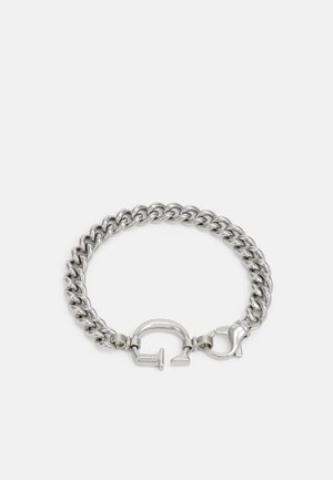 Bracciale a catena spessa in tono argento con una chiusura unica caratterizzata da un lucchetto e un fermaglio a granchio su sfondo bianco.