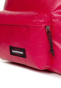 Rode Eastpak-rugzak met duurzaam nylon materiaal, een voorvak met ritssluiting en een zwart merkembleem met een wereldbolontwerp.