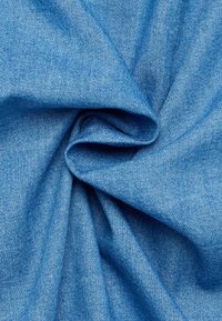 Denimstof in een levendig blauw, met een gladde textuur en een subtiel weefpatroon, samengebracht om zachtheid en flexibiliteit te tonen.