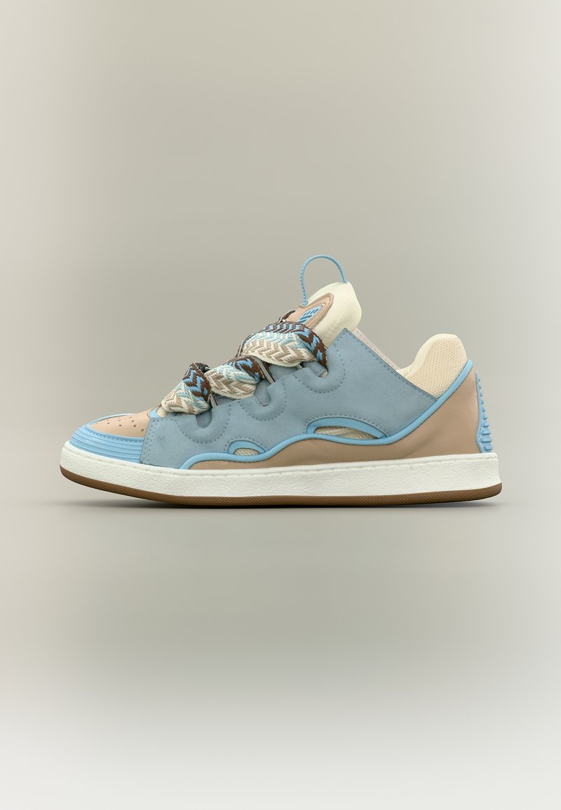 Baskets basses avec panneaux beige, bleu clair et marron clair, lacets épais texturés, semelle blanche avec semelle extérieure marron sur fond neutre.