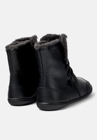 Bottes de cheville en cuir noir avec une douce doublure en fourrure grise en haut, présentant une texture lisse et un design à bout rond.