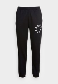 Pantaloni da jogging neri in cotone, con vita elastica e polsini alla caviglia. Stampa del logo di un uccello bianco sulla coscia sinistra.