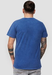 Blauwe katoenen t-shirt met korte mouwen, ronde hals en een zachte textuur. Weergeeft een effen kleur zonder patronen of accenten.