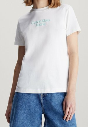 Biały bawełniany t-shirt z wyszywanym turkusowym napisem "Calvin Klein Jeans". Krótkie rękawy i luźny krój z okrągłym dekoltem.
