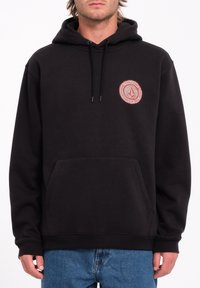 Hoodie noir en mélange de coton, avec une poche avant, des cordons de serrage et un logo circulaire rouge sur la partie gauche de la poitrine.