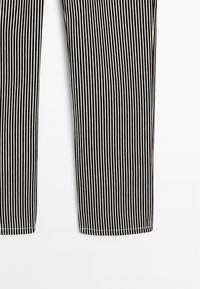 Pantaloni a righe bianche e nere realizzati in un tessuto leggero, con un design a gamba dritta e orli cuciti due volte.