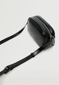 Borsa a tracolla nera in finta pelle con forma rettangolare, chiusura a zip superiore e tracolla regolabile. Texture liscia con dettagli lucidi.