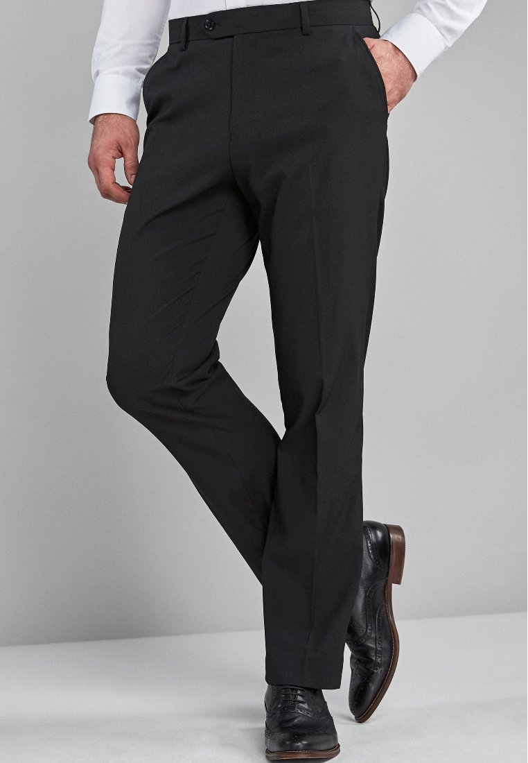 Pantalons de costume noirs avec une coupe ajustée, présentant une texture lisse, des jambes droites et des passants de ceinture, associés à des chaussures de costume noires vernies.