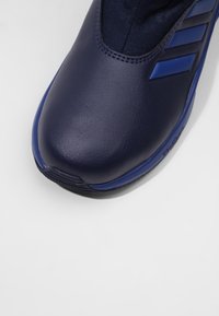 Námořnické modré sportovní boty s hladkým koženým svrškem a síťovinovými akcenty, zaoblenou špičkou a texturovanou podešví pro lepší přilnavost.