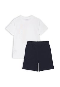 T-shirt bianca in cotone a maniche corte con un design di testo colorato, abbinata a pantaloni corti blu navy in cotone con cintura elastica.