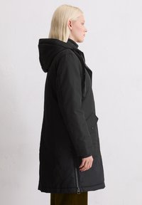 Czarna, ocieplana parka z kapturem, z bocznym zamkiem i guzikowym zapięciem z przodu. Wykonana z gładkiego, trwałego materiału; długość do kolan.