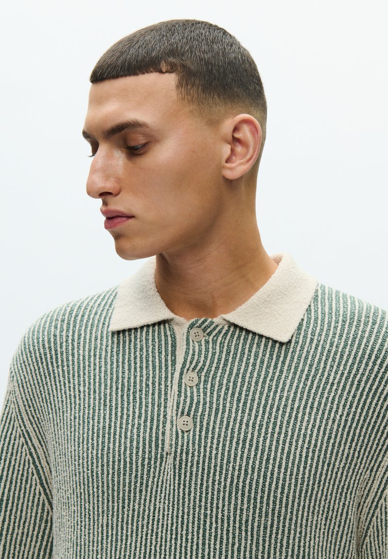 Striped knit pullover in green and cream, featuring a soft collar, three button closure, and textured vertical lines across the fabric.