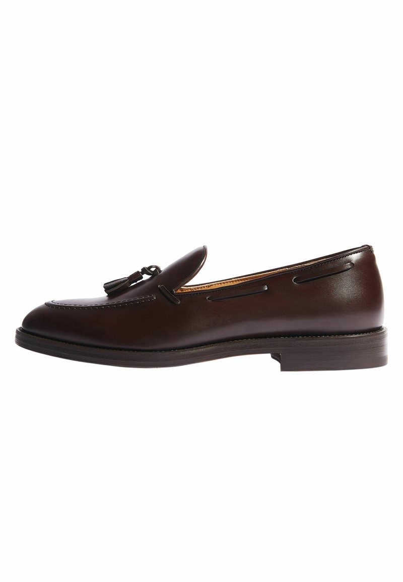 Bruine leren loafers met kwastje, ronde neus, gestikte accenten en een platte zool. Gladde textuur en klassiek ontwerp.
