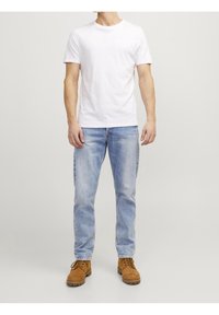 White short-sleeve T-shirt paired with light blue denim jeans and brown lace-up boots. Plain design, casual fit, and cotton material.