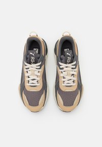 Graue und beige Sneakers mit einem Mesh-Obermaterial, strukturierten Akzenten, glatten Schnürsenkeln und gepolstertem Kragen, ausgestattet mit einem auffälligen Logo auf der Zunge.