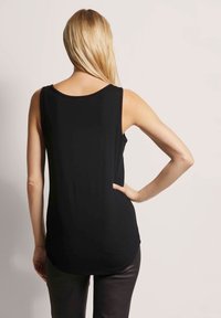 Zwarte tanktop met een ronde halslijn en mouwloos ontwerp. Kenmerkt zich door een gebogen zoom en een soepele textuur, gecombineerd met aansluitende broek.