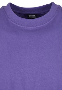 Tricou din bumbac violet cu guler rotund. Are cusături întărite și o etichetă cu inscripția "URBAN CLASSICS" la guler.
