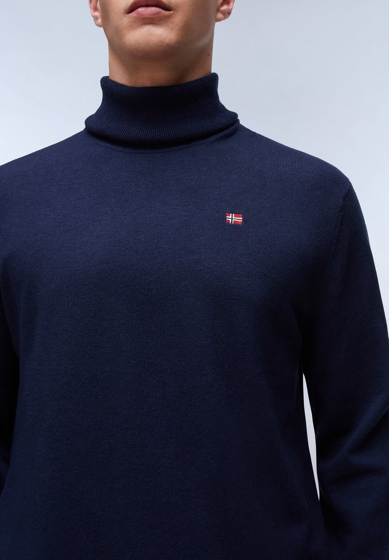 Maglione a dolcevita blu navy realizzato in tessuto lavorato a maglia; presenta una piccola bandiera norvegese ricamata sul petto.