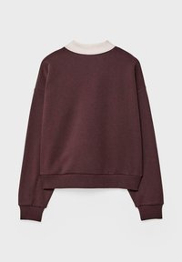 Bordo pulover z kremastim ovratnikom, oversized kroj, rebrasti manšeti in rob. Gladka tekstura, vključuje spuščena ramena in šiv na hrbtu.