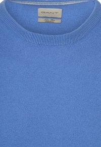 Blauer gestrickter Rundhalsausschnitt-Pullover mit GANT-Markenlabel und dem Aufkleber "Super Fine Liverpool" im Kragen.