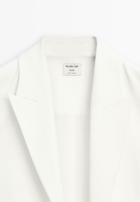 Witte blazer met een reverskraag, gemaakt van gladde stof. Voorzien van een label met de tekst "Massimo Dutti Studio", met een minimalistisch ontwerp.
