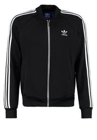 Black zip-up jacket in polyester with white stripes on sleeves. Features a round collar and front pockets. Small brand logo on chest.