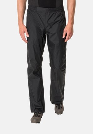 Pantaloni neri, leggeri e impermeabili con una vita elasticizzata e una texture liscia, abbinati a scarpe grigie con più cinturini e una suola robusta.