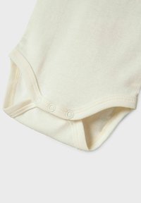 Bodysuit pour bébé de couleur crème en coton doux et extensible. Présente des fermetures à pression en bas et un bord côtes le long des bords. Texture lisse.