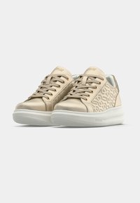 Beige sneakers with a smooth leather finish, featuring a patterned design, rounded toe, gold eyelets, and a white thick sole.