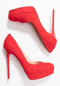 Les escarpins en suédine rouge présentent un design à plateforme et un talon aiguille vernissé rouge. Forme de bout arrondi avec une doublure intérieure lisse.