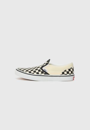 Černo-bílé kostkované slip-on boty s béžovým plátnem, bílou gumovou podrážkou a malým logem Vans na boku.