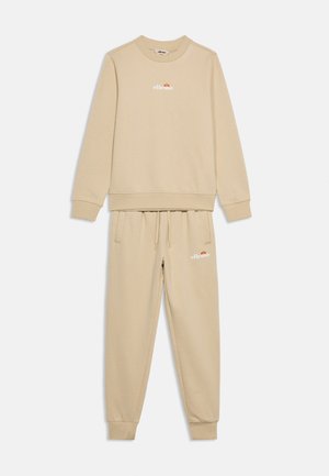 Beežihall dressipluus ja püksid elastsete mansettide, paelaga vöökohaga ning valge Ellesse logoga rinnal ja reiel.